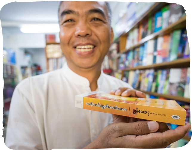 Langham scholar holding a book in a library